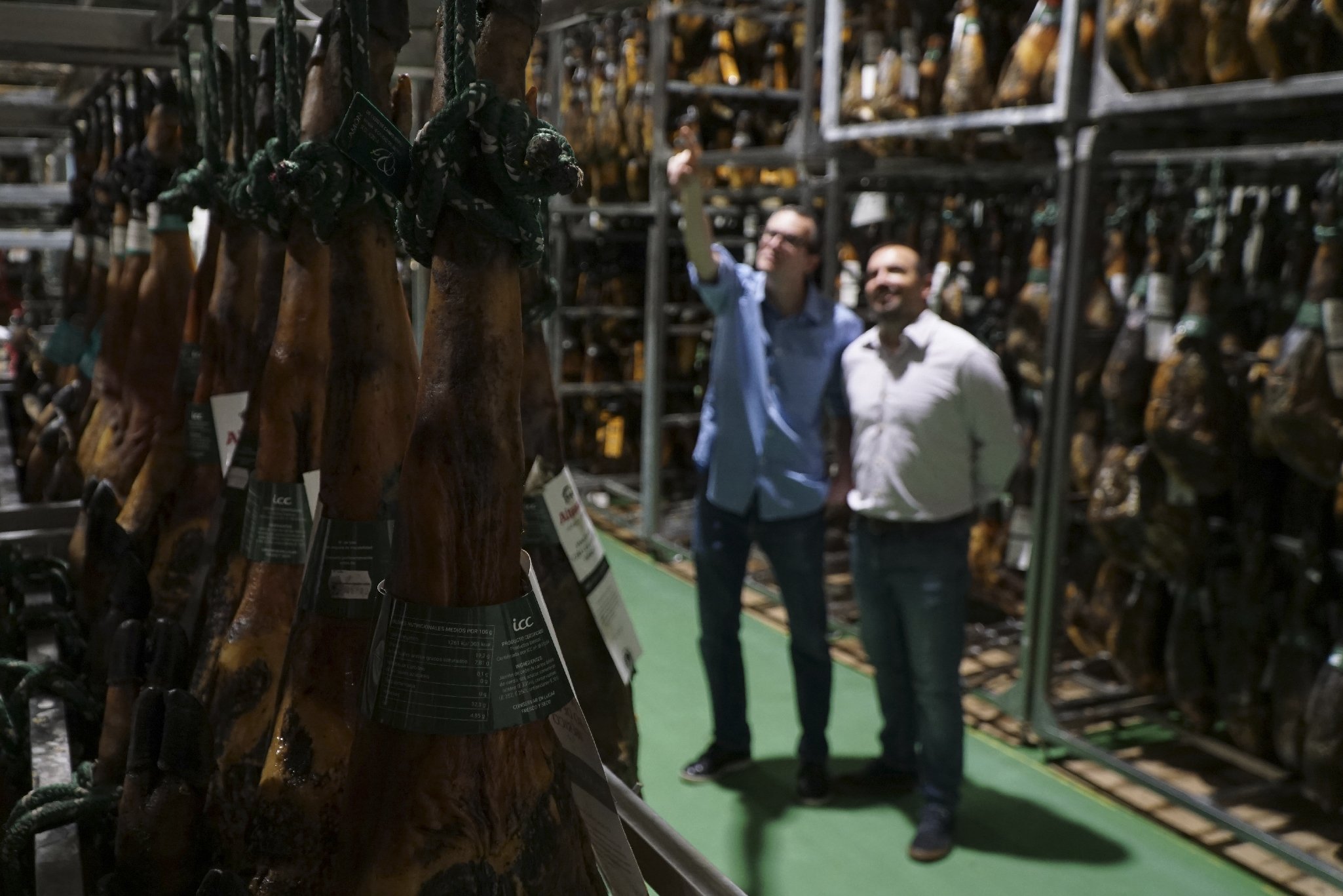 Miquel and Jose María checking hams in the warehouse.